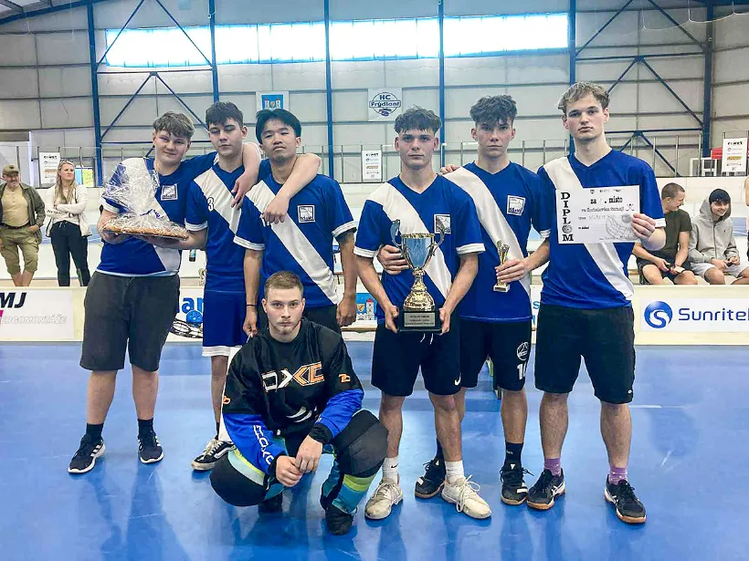 Vítězný tým s trofejí a diplomem.
